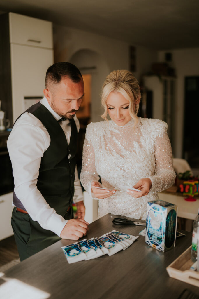 Frane i Maja Mesić na dan vjenčanja otvaraju Disney Lorcana paketić i smiju se, odjeveni u vjenčanicu i odijelo